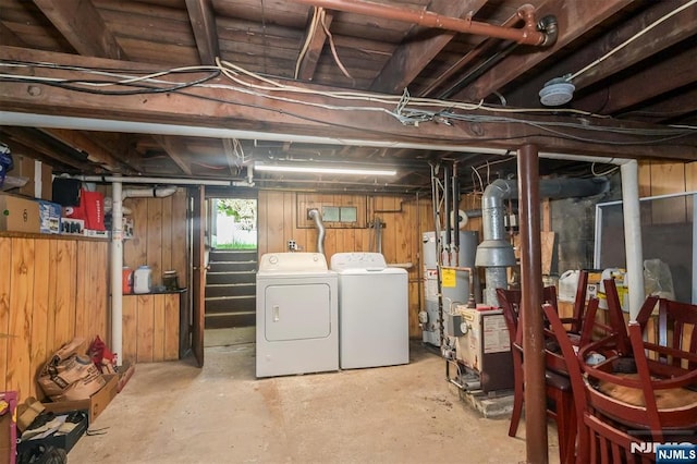 below grade area featuring gas water heater, separate washer and dryer, wooden walls, and a heating unit