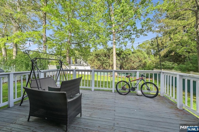 deck featuring a lawn and view of wooded area