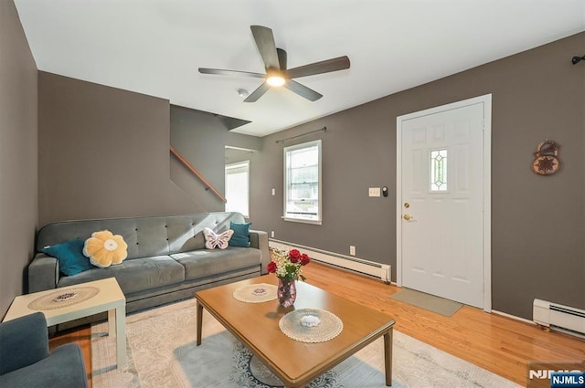 living area featuring a baseboard heating unit, light wood finished floors, and ceiling fan