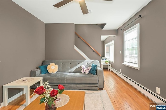 living room with a baseboard heating unit, a ceiling fan, and wood-type flooring