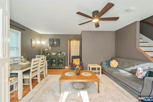 living room with a ceiling fan, stairs, and wood finished floors