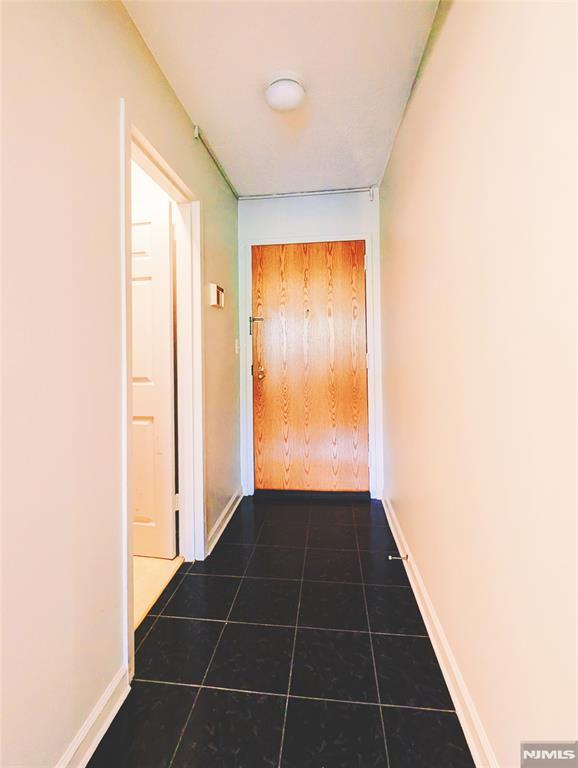 300 Main St Unit 216, Little Falls, NJ 07424 - hall featuring dark tile patterned flooring and baseboards