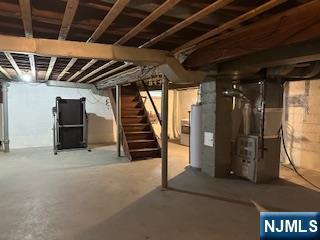 unfinished basement featuring water heater, stairway, and heating unit