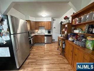 kitchen with stainless steel appliances, light wood-type flooring, brown cabinets, light countertops, and a sink