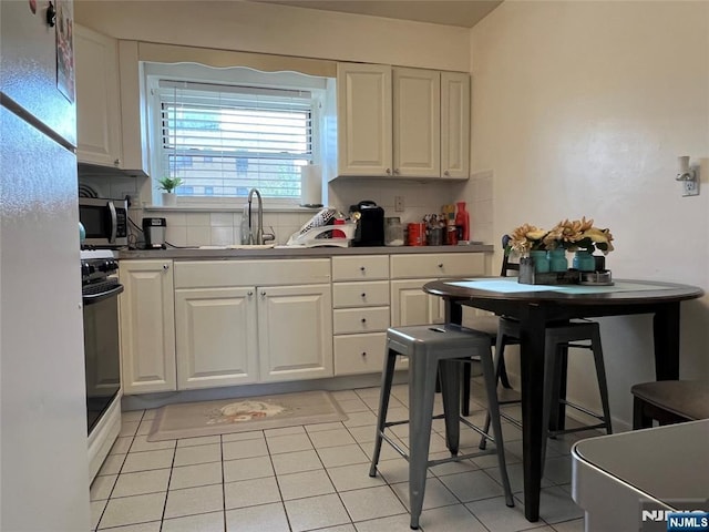 2430 8th St Unit 5B, Fort Lee, NJ 07024 - kitchen with stainless steel microwave, a sink, range, white cabinets, and decorative backsplash