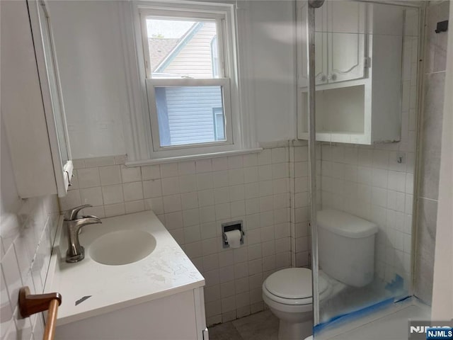 bathroom with tile walls, toilet, and vanity