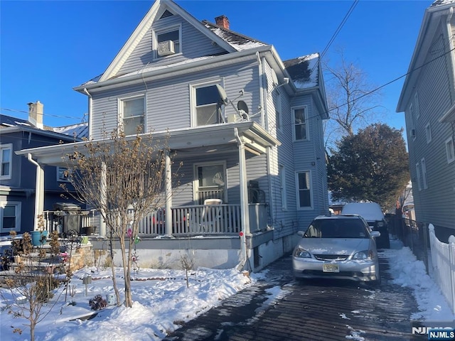 traditional style home with covered porch, a chimney, and fence
