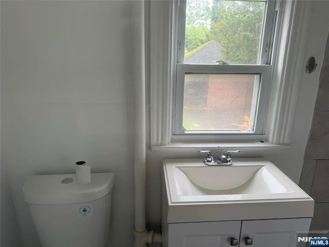 bathroom with healthy amount of natural light, toilet, and vanity
