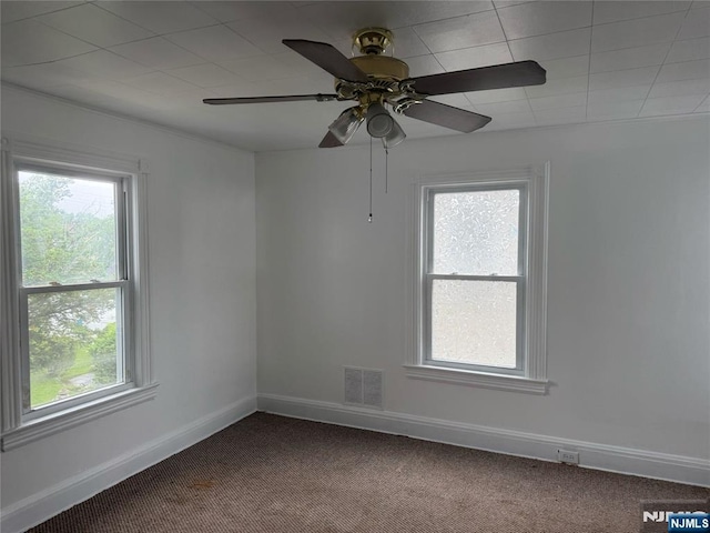 carpeted spare room with plenty of natural light, baseboards, and ceiling fan