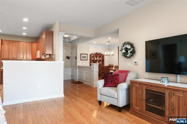 living room with light wood-type flooring, recessed lighting, a chandelier, and a wainscoted wall