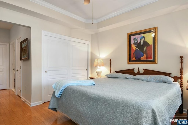 bedroom featuring light wood-type flooring, ornamental molding, baseboards, a closet, and a ceiling fan