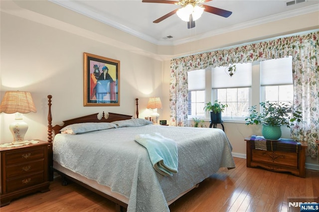 bedroom with hardwood / wood-style floors, ornamental molding, baseboards, and a ceiling fan