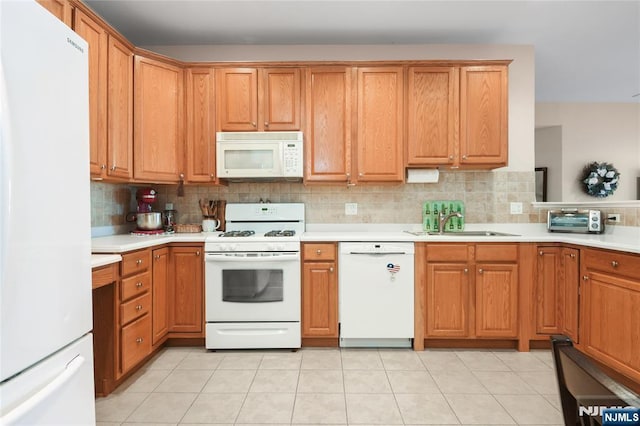 kitchen featuring white appliances, a sink, tasteful backsplash, and light countertops