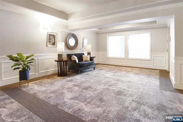 living area with a decorative wall, carpet, wainscoting, and ornamental molding