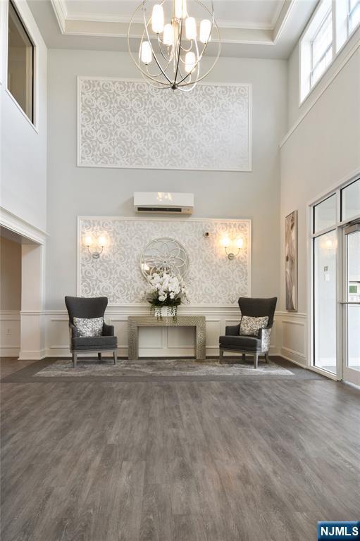 common area featuring a towering ceiling, crown molding, a decorative wall, and wainscoting