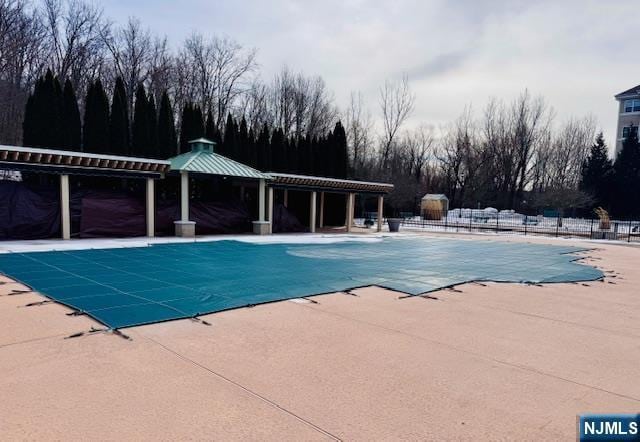 community pool with a patio area, fence, and a gazebo