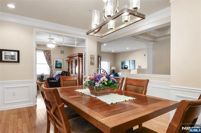 dining room featuring plenty of natural light, ornamental molding, hardwood / wood-style flooring, wainscoting, and a chandelier