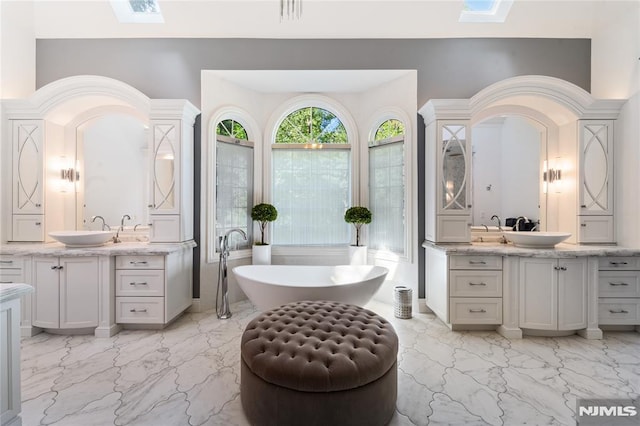 14 Stewart Ct, Old Tappan, NJ 07675 - bathroom with a skylight, marble finish floors, two vanities, and a freestanding tub