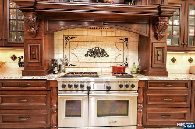 70 Oak Dr, Upper Saddle River, NJ 07458 - kitchen featuring range with two ovens, decorative backsplash, glass insert cabinets, and light stone countertops