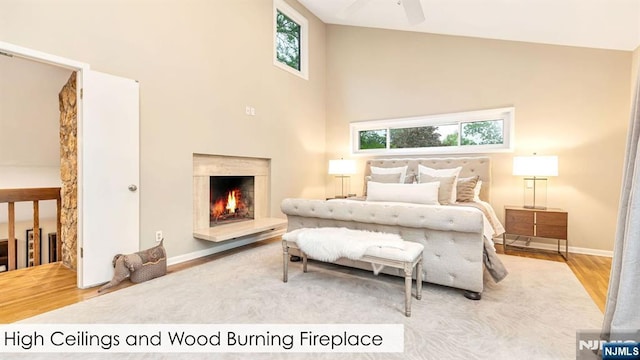 108 Buckhaven Hl, Upper Saddle River, NJ 07458 - bedroom with wood finished floors, multiple windows, a towering ceiling, a lit fireplace, and baseboards