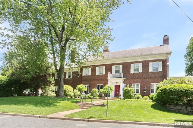 927 Commonwealth Dr Unit 4, Teaneck, NJ 07666 - georgian-style home featuring a chimney, brick siding, and a front yard