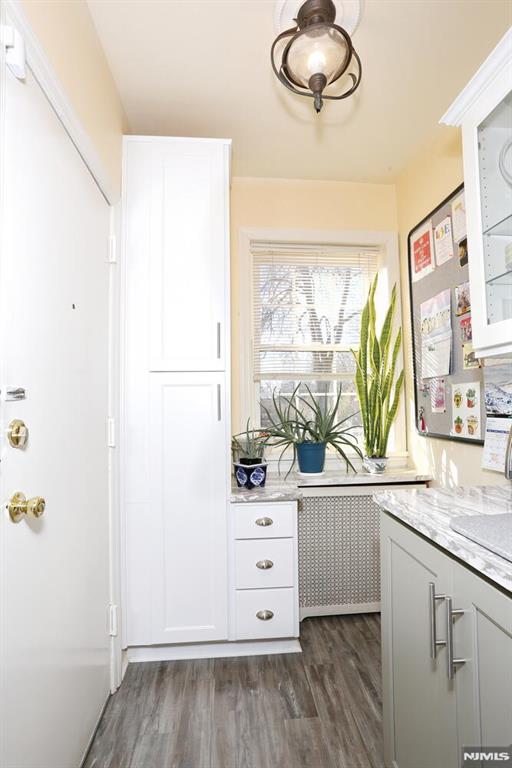 927 Commonwealth Dr Unit 4, Teaneck, NJ 07666 - kitchen with dark wood-style floors, light stone countertops, white cabinets, and glass insert cabinets
