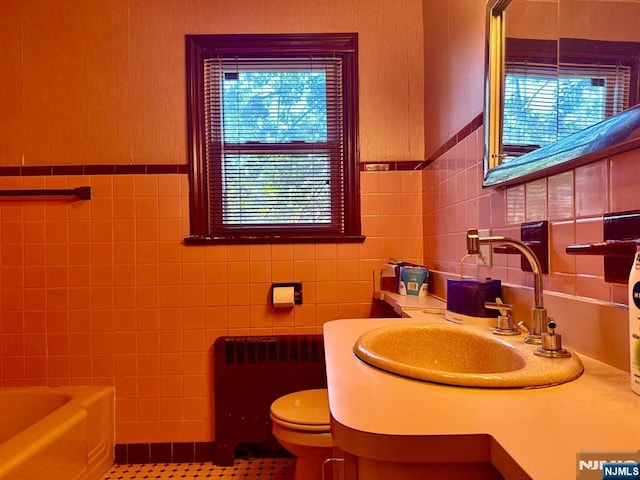 384 Audubon Rd, Englewood, NJ 07631 - bathroom featuring tile walls, radiator, toilet, a tub to relax in, and tile patterned floors