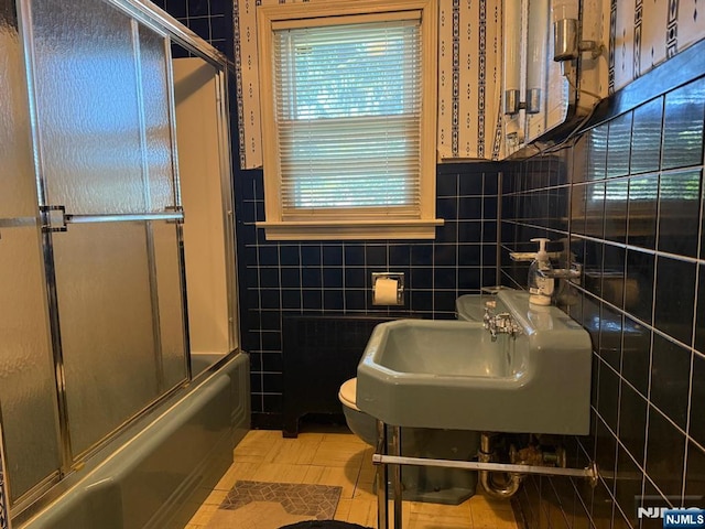 384 Audubon Rd, Englewood, NJ 07631 - bathroom with tile walls, toilet, radiator, a sink, and combined bath / shower with glass door