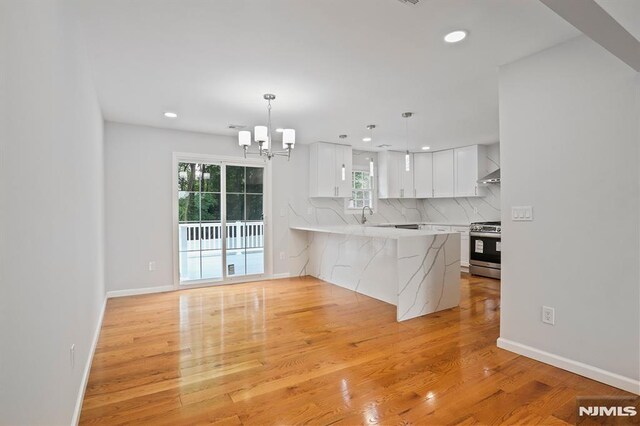kitchen with stainless steel gas range, light wood-type flooring, a chandelier, white cabinets, and recessed lighting
