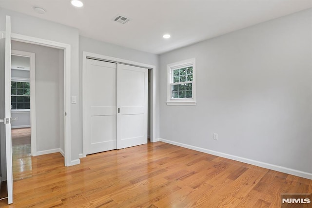 unfurnished bedroom featuring baseboards, light wood finished floors, a closet, and recessed lighting