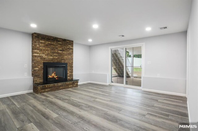 unfurnished living room featuring wood finished floors, a fireplace, recessed lighting, and baseboards