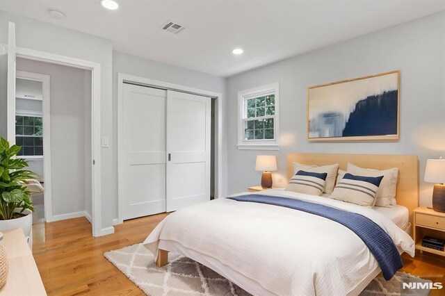 bedroom with light wood finished floors, a closet, baseboards, and recessed lighting