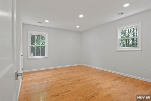 spare room featuring plenty of natural light, light wood finished floors, recessed lighting, and baseboards