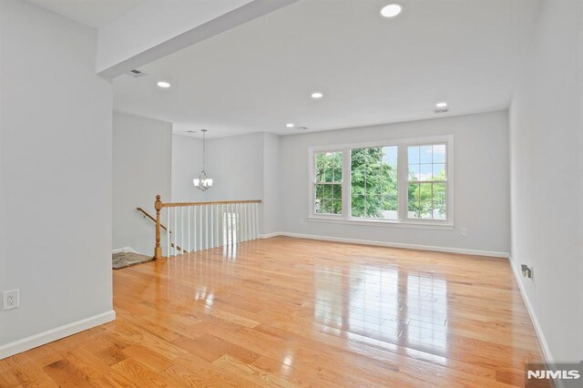 unfurnished room with a chandelier, wood finished floors, recessed lighting, and baseboards