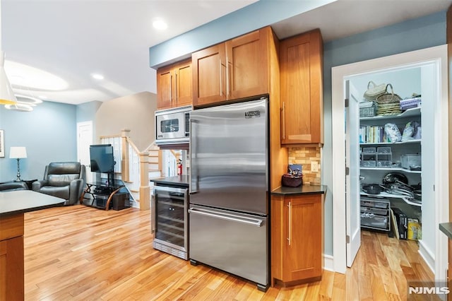 8709 Churchill Rd, North Bergen, NJ 07047 - kitchen with built in appliances, beverage cooler, light wood-type flooring, brown cabinets, and open floor plan