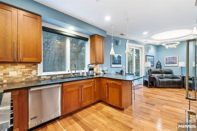 8709 Churchill Rd, North Bergen, NJ 07047 - kitchen featuring stainless steel dishwasher, a sink, open floor plan, brown cabinetry, and dark countertops