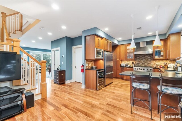 8709 Churchill Rd, North Bergen, NJ 07047 - kitchen featuring built in appliances, wall chimney exhaust hood, dark countertops, brown cabinetry, and wine cooler