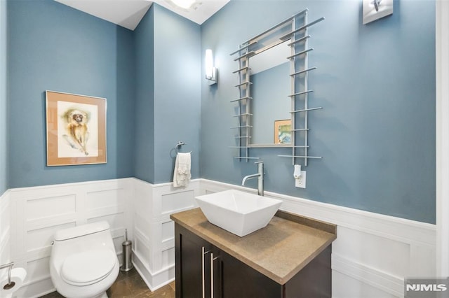 8709 Churchill Rd, North Bergen, NJ 07047 - bathroom with a decorative wall, toilet, wainscoting, and vanity