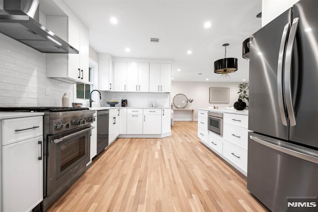 246 Oakwood Dr, Paramus, NJ 07652 - kitchen with appliances with stainless steel finishes, wall chimney exhaust hood, light countertops, light wood-style floors, and tasteful backsplash