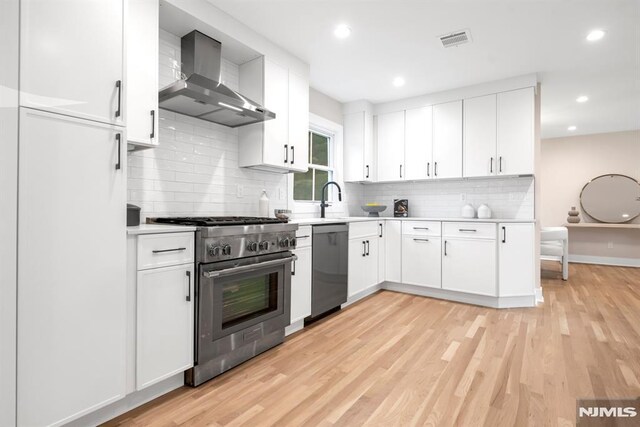 246 Oakwood Dr, Paramus, NJ 07652 - kitchen featuring high end stainless steel range oven, wall chimney exhaust hood, dishwasher, light countertops, and light wood-style flooring