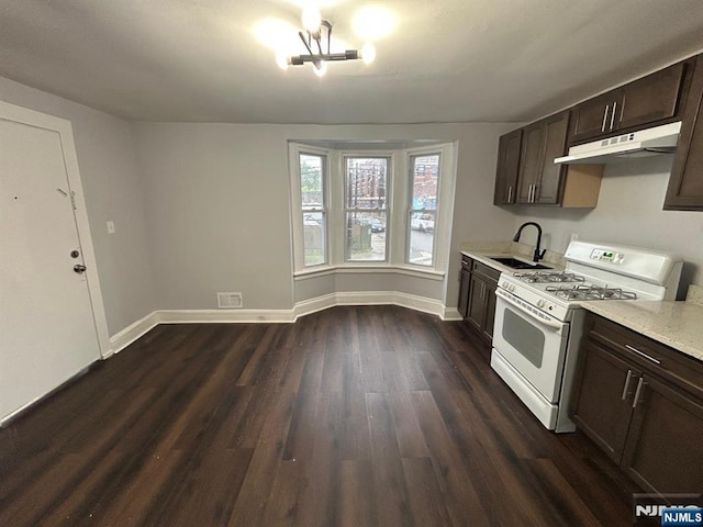 257 New St, Orange, NJ 07050 - kitchen with white gas range, under cabinet range hood, a sink, dark wood-style floors, and dark brown cabinetry