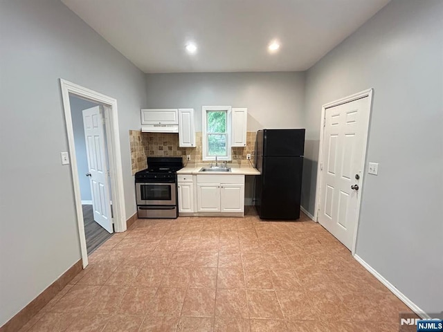257 New St, Orange, NJ 07050 - kitchen with gas range, freestanding refrigerator, a sink, under cabinet range hood, and white cabinetry