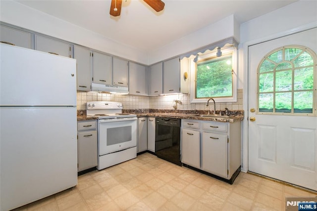 kitchen with white appliances, a sink, dark countertops, light flooring, and under cabinet range hood