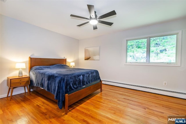 bedroom with a baseboard heating unit, light wood-style floors, and ceiling fan