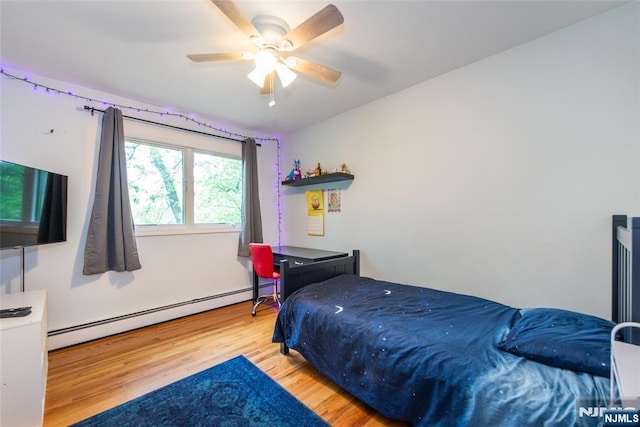 bedroom featuring a baseboard heating unit, wood finished floors, and ceiling fan