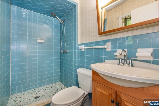 bathroom featuring tiled shower, toilet, wallpapered walls, and vanity