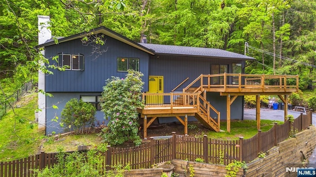 back of house featuring a deck, a chimney, and a fenced backyard