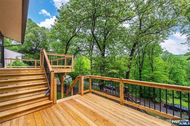 wooden deck featuring view of scattered trees and stairway