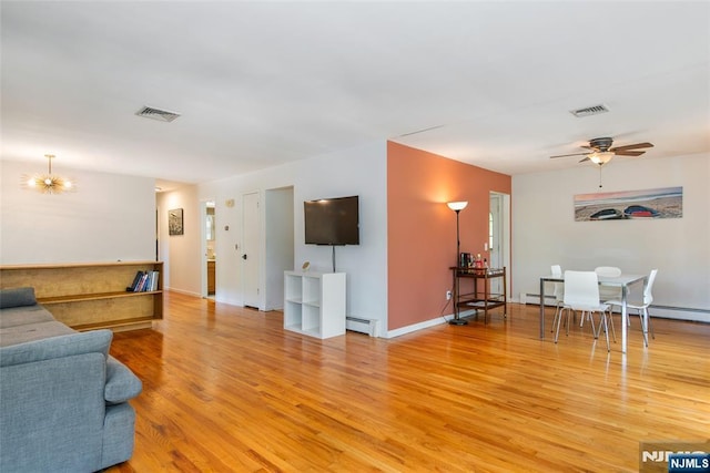 living area with light wood-style flooring, baseboard heating, a ceiling fan, and a chandelier