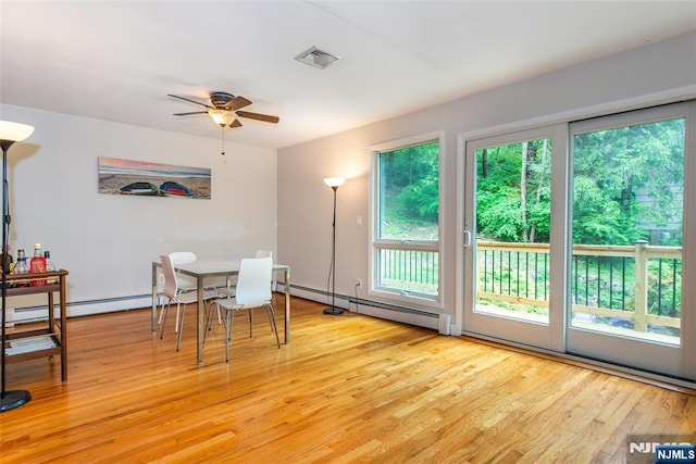 dining room featuring healthy amount of natural light, ceiling fan, light wood-style flooring, and baseboard heating